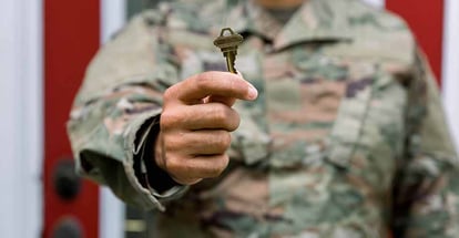A close view of soldier holding key in front of home
