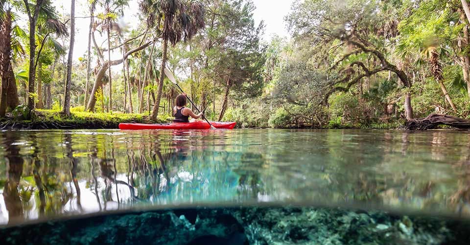 A girl kayaking in a lake near an underwater cave formation in Chassahowitzka River Florida