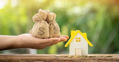 A hand hold money bag and gold coins around home model