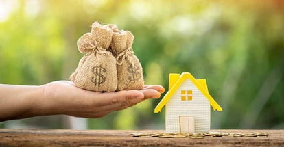 A hand hold money bag and home model