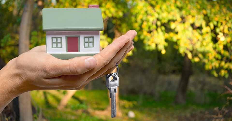 A hand holding a model house and key