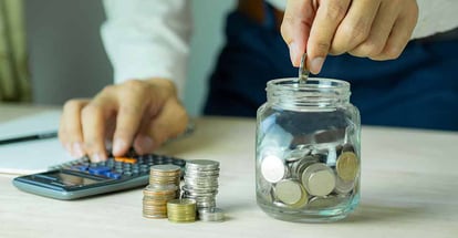 A hand put coin in glass jar for saving