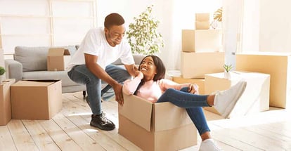 A happy black couple playing together with cardboard box in their new house