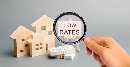 A magnifying glass is looking at a poster with the word Low rates and wooden house