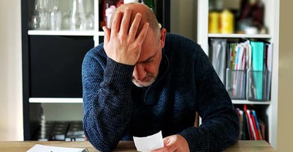 A man holding receipts and is upset due to inflation