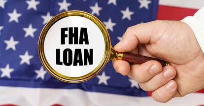 A man holds a magnifying glass with the inscription FHA Loan