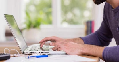 A man working from home on a laptop computer sitting at a desk