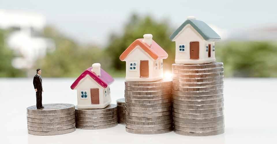 A miniature figure stand on top of stack of coins and looking to the house