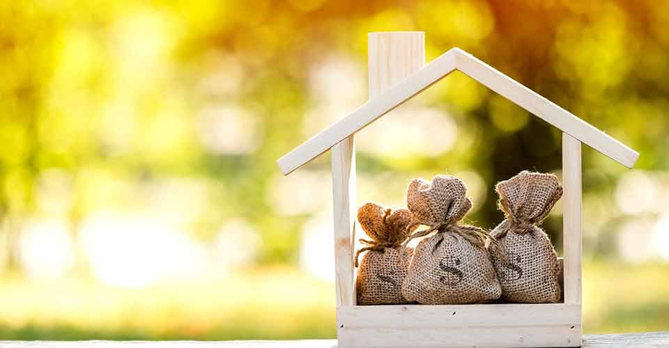 A money bags put in a model home on the table for real estate investment