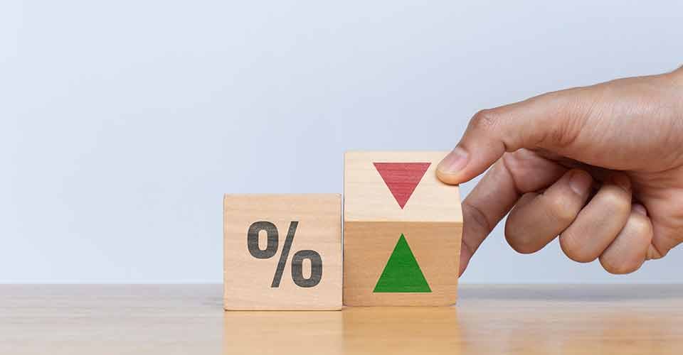 A person flip wooden cube with down arrow to up arrow and percentage symbol