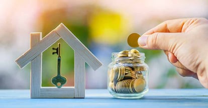 A person hand hold a coin and wooden model house with key
