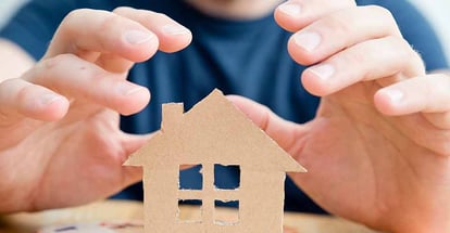 A person hand repairing cardboard house