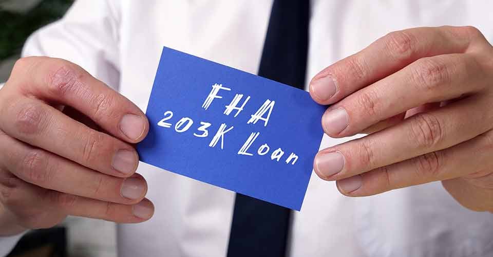 A person holding a paper sheet with FHA 203K Loan written