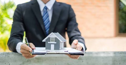 A person holding a renovation loan agreement and model home