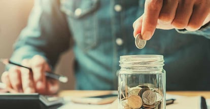 A person holding coins putting in glass for down payment