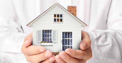 A person holding model house representing home ownership