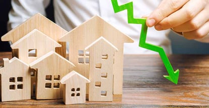 A person holds down arrow near the wooden houses
