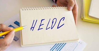 A person pointing at HELOC text on notebook