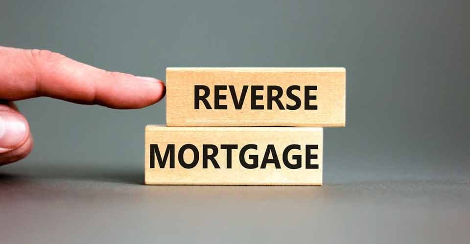A person pointing at reverse mortgage words on wooden blocks