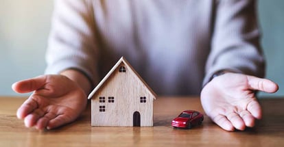 A person showing wooden house model on the table