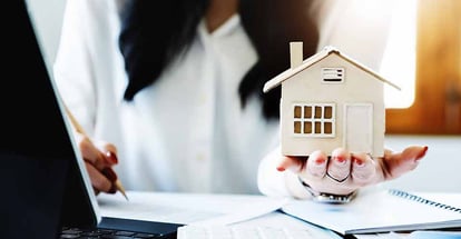 A real estate agent holding a home model