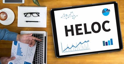 A screen with HELOC word and documents on table