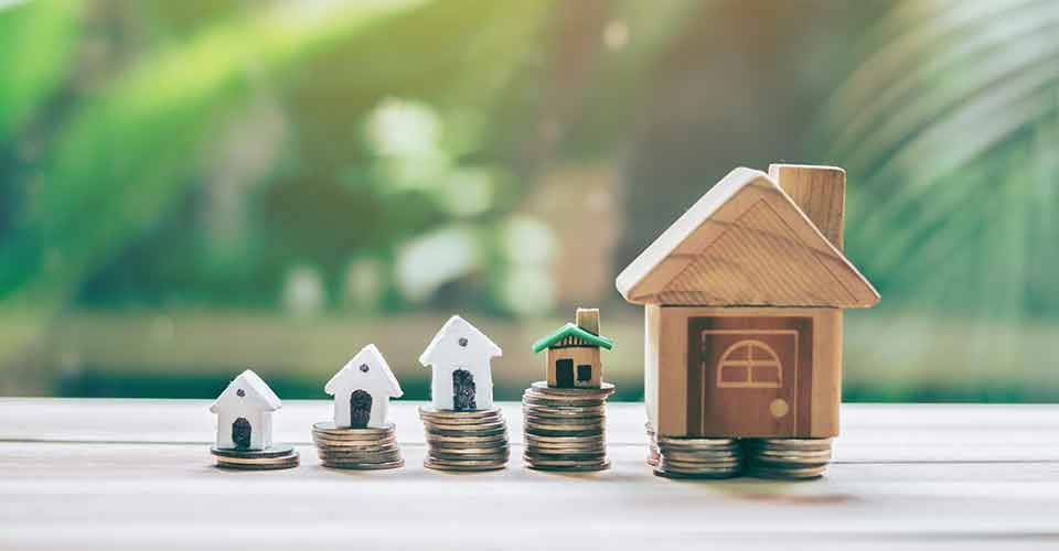 A wooden house model placed on top of coin stack