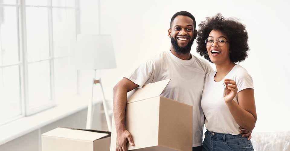 African American Couple Posing with Moving Boxes and New House Key