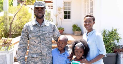 African American soldier wearing uniform and his family standing by their house
