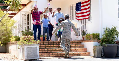 African American solider wearing uniform with family outside their new house