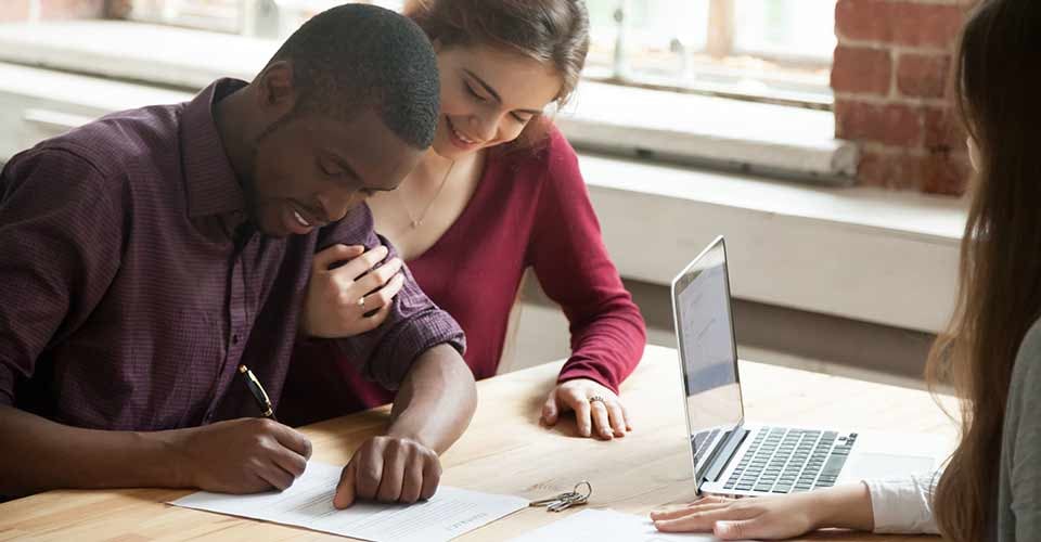 African american man signing home purchase agreement in front of realtor