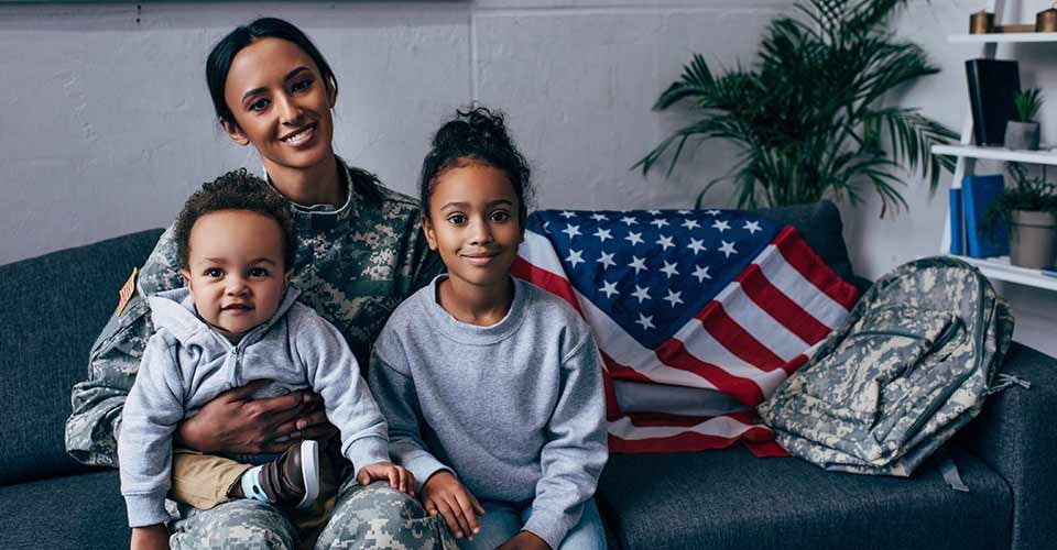 African american mother in military uniform sitting with her kids in new home