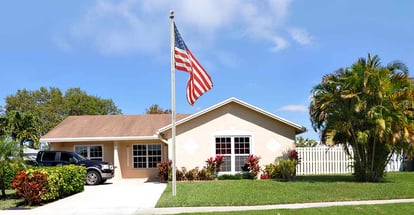 Beautiful suburban ranch style home with american flag pole in residential neighborhood