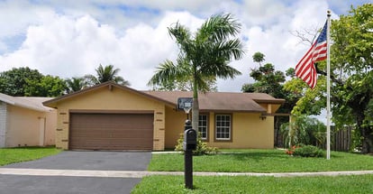 Beautiful suburban ranch style home with palm tree in residential neighborhood