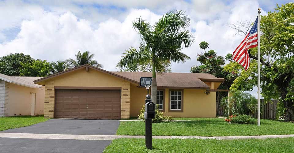 Beautiful suburban ranch style home with palm tree in residential neighborhood