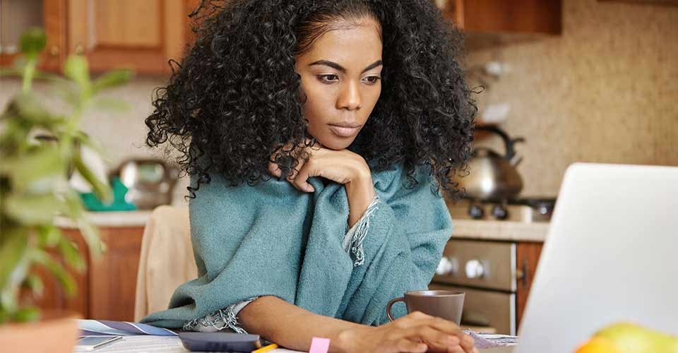 Beautiful young dark skinned woman looking at screen with serious concentrated expression