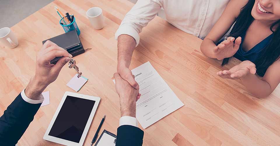 Broker giving keys of new house and handshaking with customer