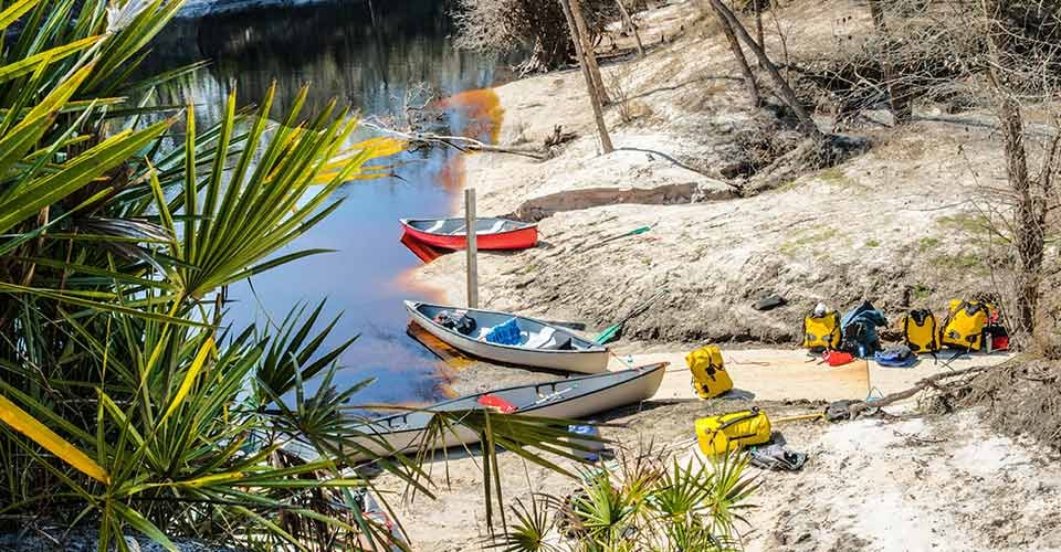 Canoes and gear packs on beach ready for a trip down the Swannee River in Florida