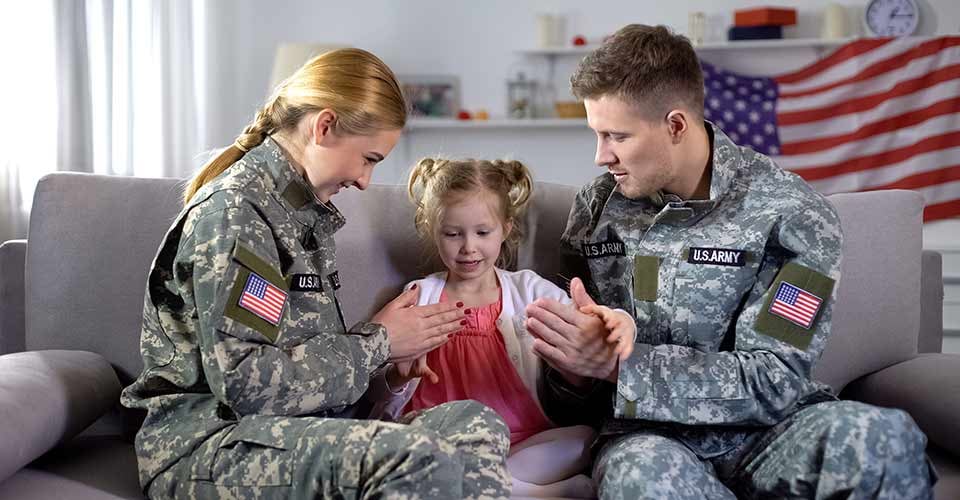 Cheerful military couple playing with little daughter at new home