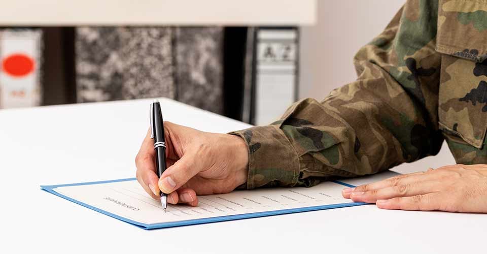 Close up of a hand of a military man signing a home purchase document