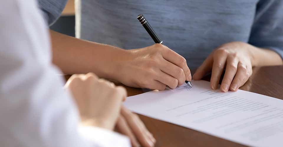 Close up of a person signing house purchase contract