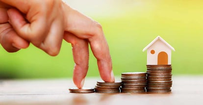 Close up of hand with climb up on a stacking gold coins to buy a house