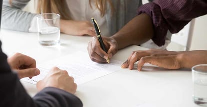 Close up of person signing ownership contract for buying first house
