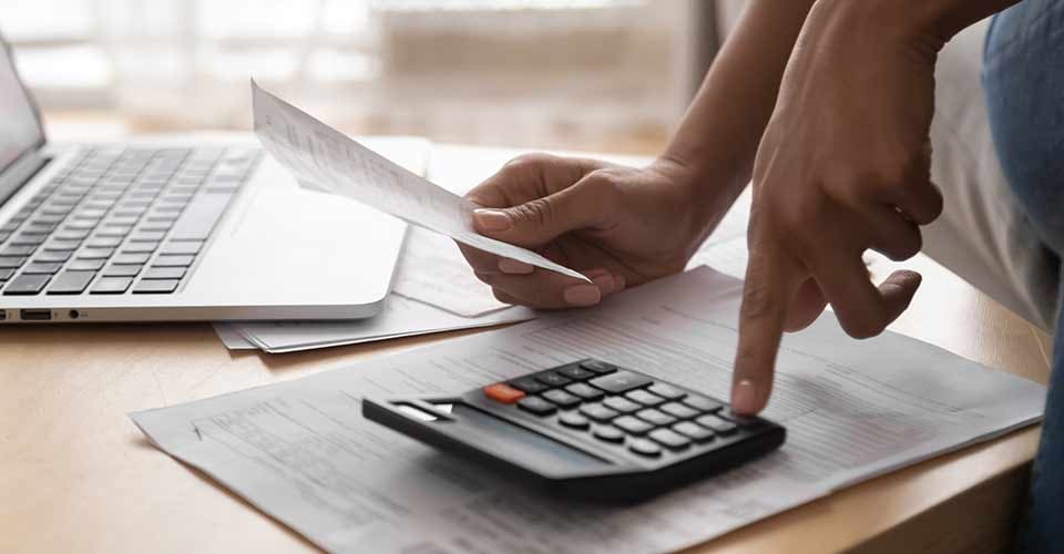 Close up view of woman holding paper bills using calculator