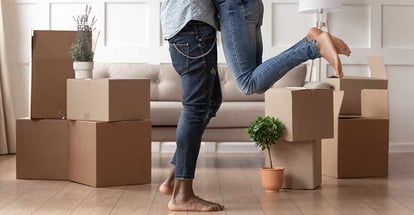 Close up young husband lift wife surrounded by cardboard boxes excited to move in new house