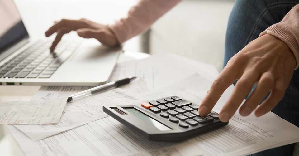 Close up young woman calculating sitting at table full of papers