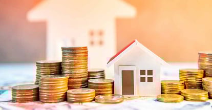 Coin stack on banknotes with house model on table