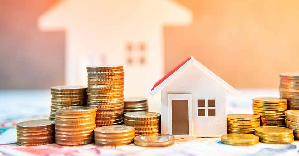 Coin stack on banknotes with house model on table