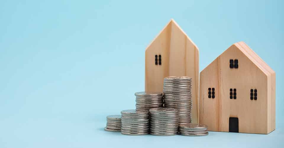 Coins stack in front of model home on wooden table