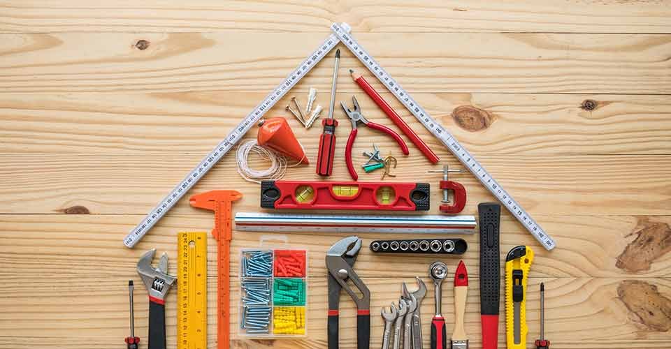 Construction tools as house model on wooden background for home renovation